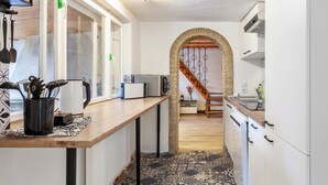 Une cuisine étroite avec des meubles blancs, un plan de travail en bois et un sol à motifs.