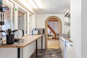 Une cuisine étroite avec des meubles blancs, un plan de travail en bois et un sol à motifs.