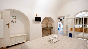 Een slaapkamer met een bed, een televisie, een stenen openhaard en boekenkasten.
