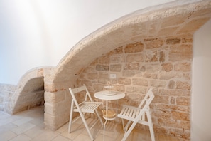 Une arche en pierre, avec une table blanche et deux chaises blanches, dans une pièce.