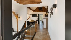 A modern interior with a staircase, wooden beams, a dining area, and a kitchen. - Vogtlandstadl – Modern Lakeside Holiday Home in Vogtland, Spacious & Comfortable (Bad Brambach)
