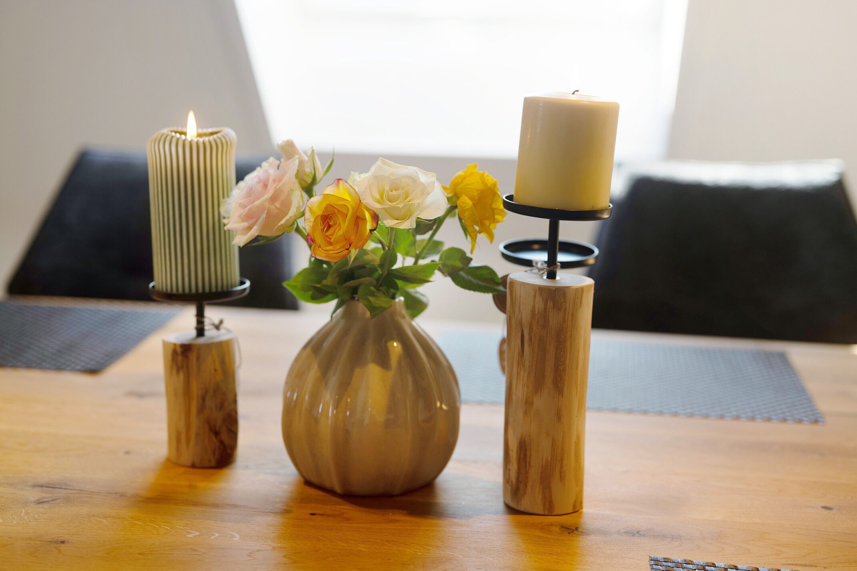 A table with candles, a vase with flowers, and a wooden vase.