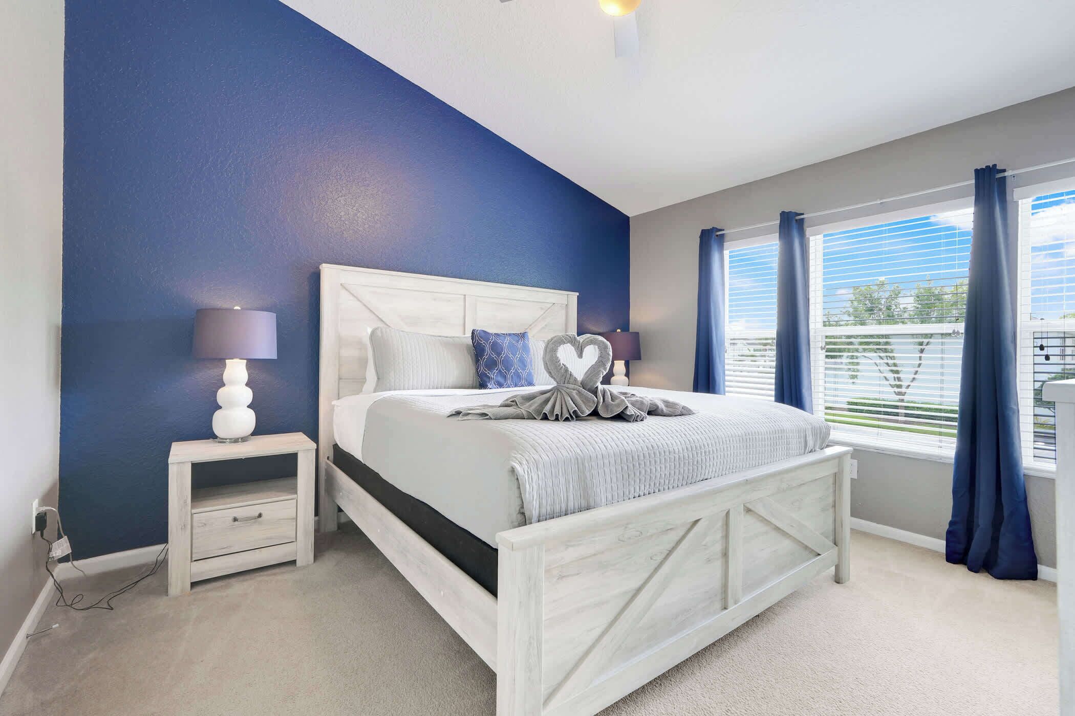 A bedroom with a bed, nightstand, and window with curtains.