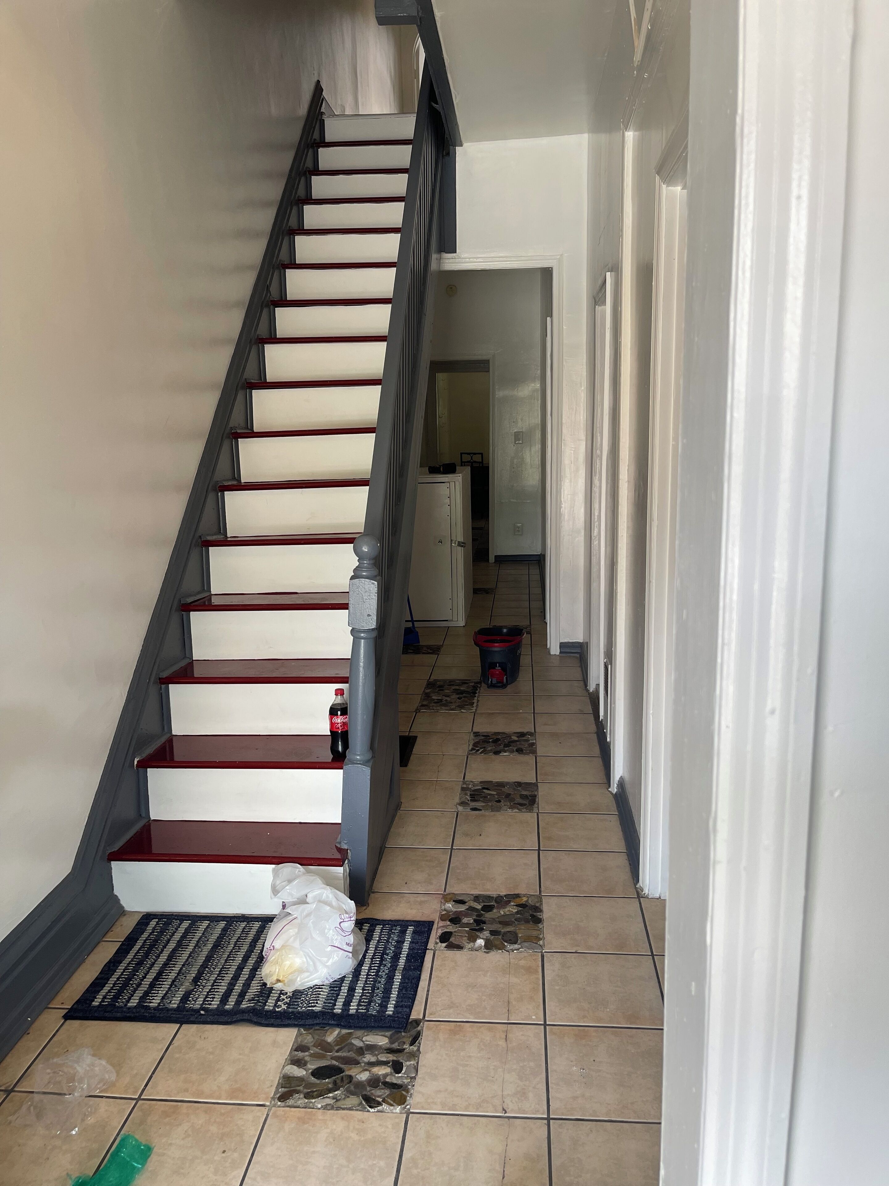 A staircase with a handrail, leading to a room with a door.