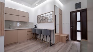 Una cocina moderna con una isla central, taburetes de bar y una puerta de madera.