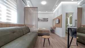 Una habitación de hotel moderna con sofá, una mesita, cama y espejo.
