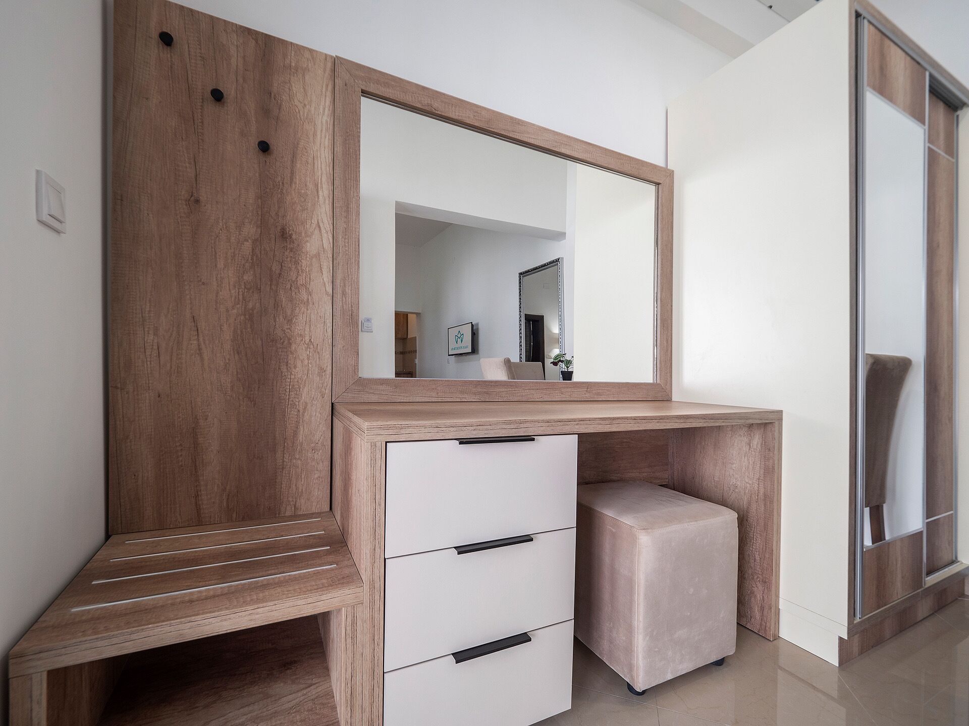 Een moderne wastafel met een houten aanrechtblad, een spiegel en een ingebouwde opbergkast met lades en een bankje.