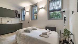 Un dormitorio moderno con cama, mesitas de noche y vistas al exterior a través de ventanas.