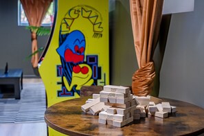 Una habitación con una mesa redonda de madera, una pared amarilla con un personaje de dibujos animados y una ventana con cortinas.
