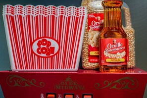 Un contenedor de palomitas, una botella de maíz para palomitas Gourmet Orville Redenbacher y un paquete de granos de maíz para palomitas.