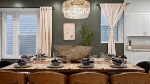 Une salle à manger avec une grande table ronde en osier qui sert de centre de table, entourée de chaises en bois.