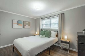 Ein modernes Schlafzimmer mit Bett, Nachttischen, einem Schminktisch und Kunstwerken an der Wand.