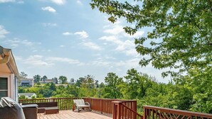 A wooden deck with a railing, a grill, and outdoor furniture.