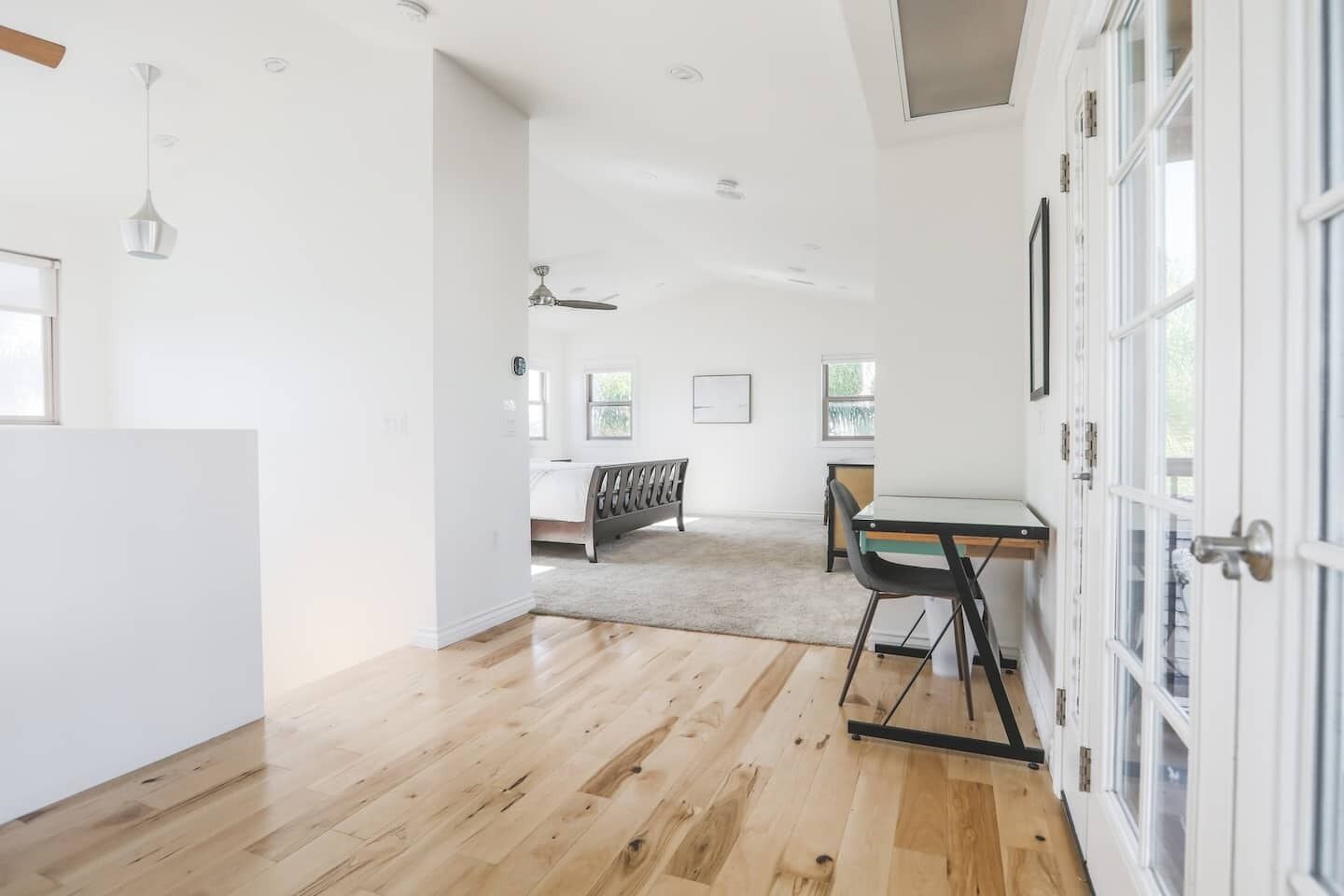 Een ruime kamer met houten vloeren, een eethoek met een tafel en stoelen, en een bed op de achtergrond.