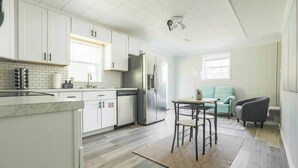Een moderne keuken met witte kasten, een roestvrijstalen koelkast en een eethoek met een tafel en stoelen.