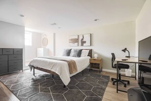 Une chambre à coucher comprenant un lit, une table de chevet, un bureau, une chaise et une commode.