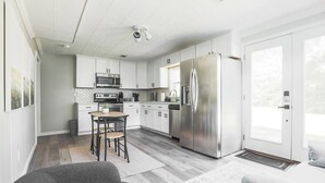 Een moderne keuken met witte kasten, roestvrijstalen apparatuur en een eethoek met een tafel en stoelen.
