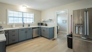 Una cocina moderna con armarios grises, un refrigerador de acero inoxidable y un microondas integrado.