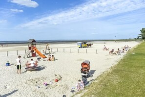 En strand med en legeplads, hestevogn og folk der slapper af.