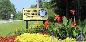 Señal para el Jardín Botánico de Columbus, con una variedad de flores coloridas al frente.