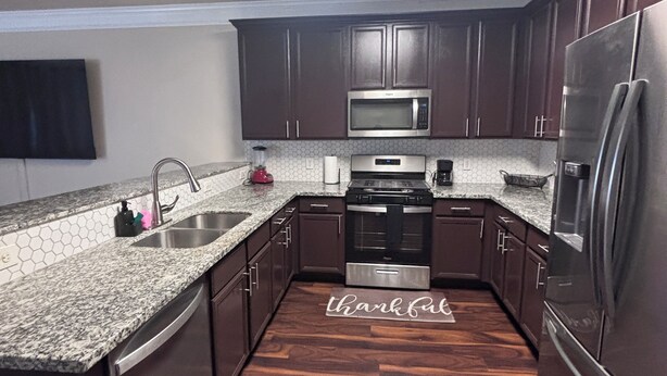 A modern kitchen with dark wooden cabinets, stainless steel appliances, and a granite countertop. - 5bd Beautiful Modern house in Spring/The Woodlands (Spring)