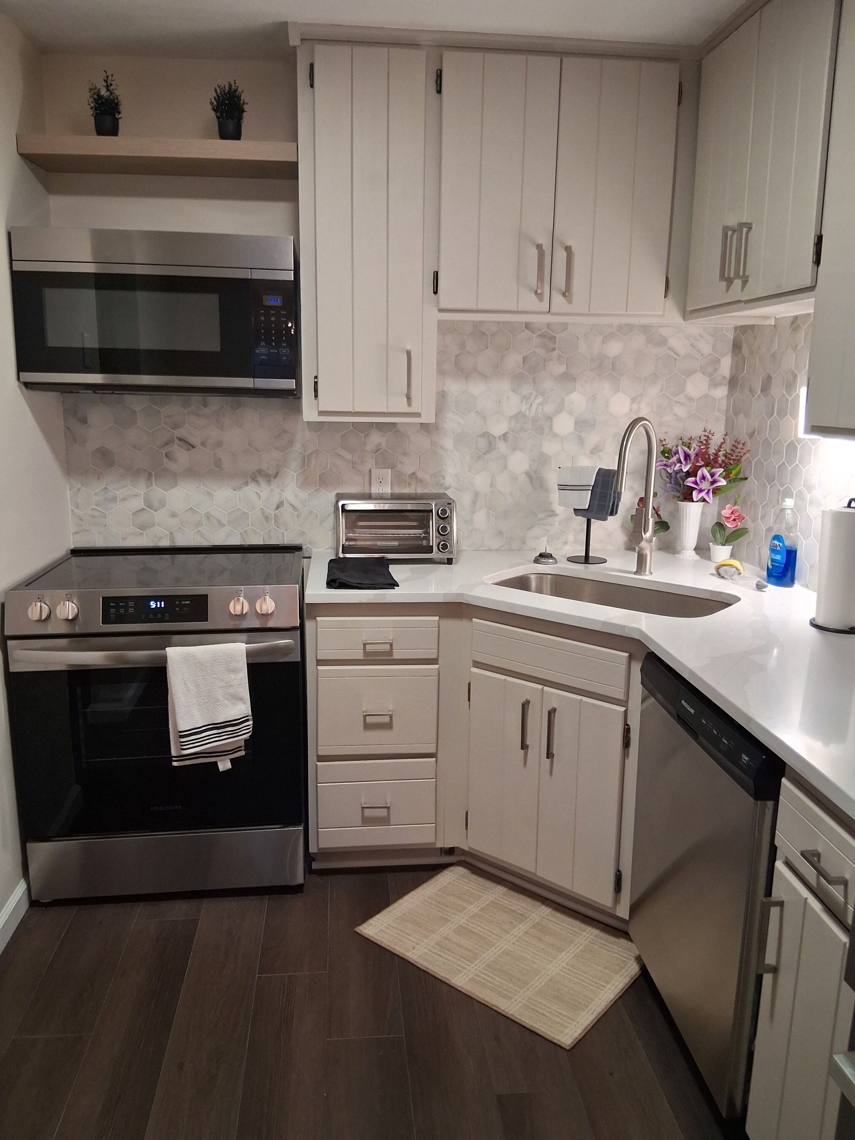 Una cocina moderna con electrodomésticos de acero inoxidable, armarios blancos y salpicadero de azulejos.