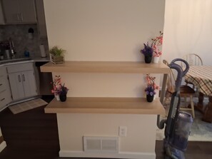A kitchen with wooden shelves holding potted plants and a vacuum cleaner. - Tranquil 2-bedroom apartment with AC in vibrant Minneapolis (Minneapolis)