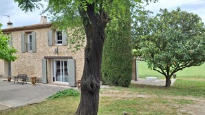 A stone building with a door and windows, surrounded by trees and a lawn. - Rent in Mas Provençal in the heart of the Luberon, apartment 2 Rooms (Pertuis)