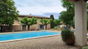 A swimming pool with a stone building in the background, surrounded by trees and a pergola. - Rent in Mas Provençal in the heart of the Luberon, apartment 2 Rooms (Pertuis)
