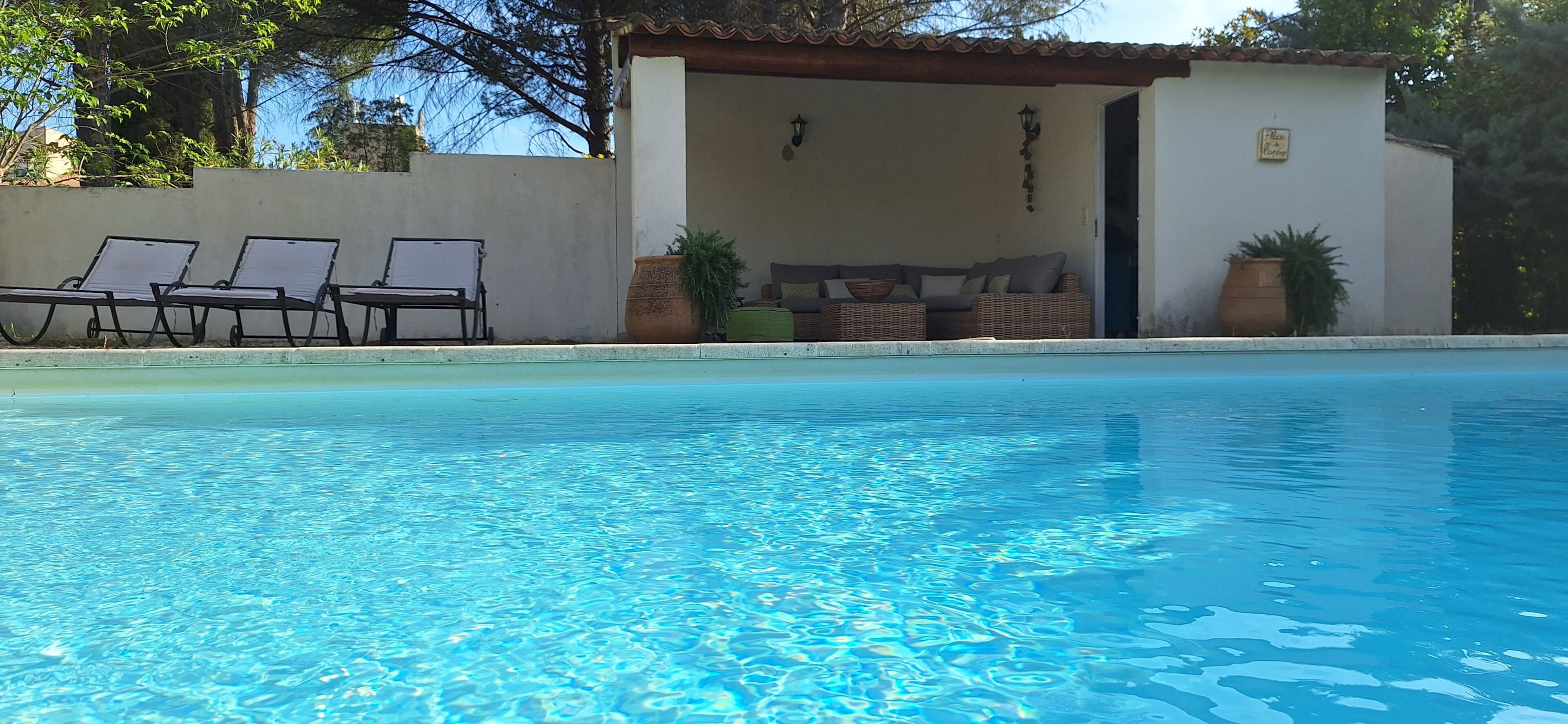 Una piscina nítida amb gandules i una zona de seients coberta.