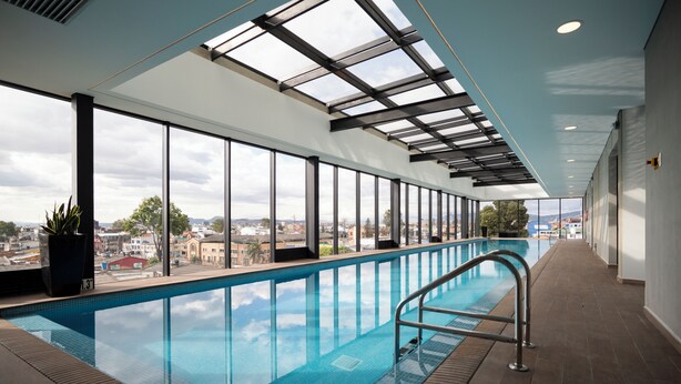 Una piscina interior con vistas a la ciudad a través de amplias ventanas.