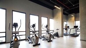 Un gimnasio con bicicletas estáticas, cintas de correr y una máquina de remo.