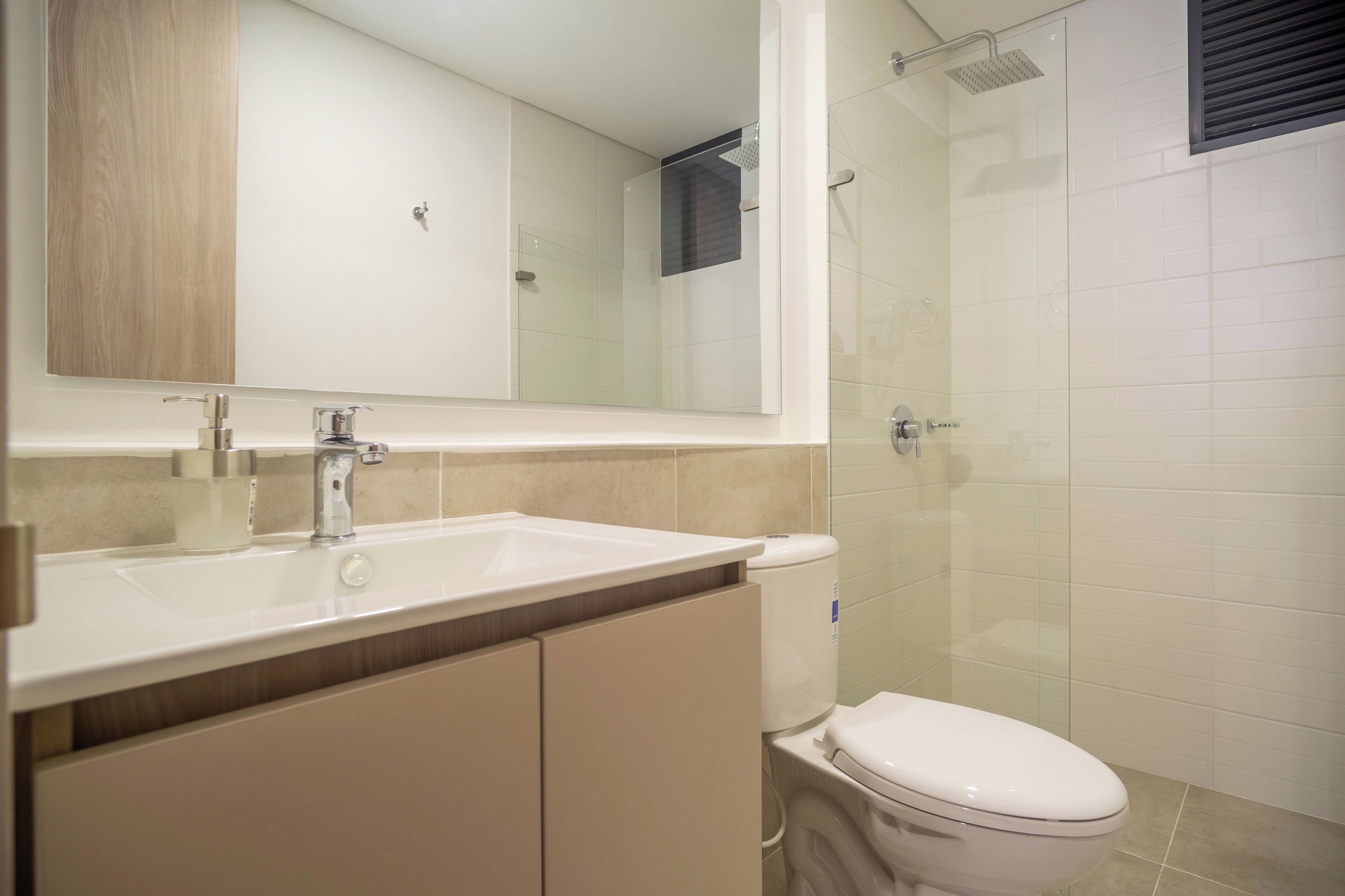 A modern bathroom with a sink, mirror, and toilet.