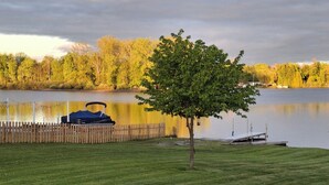 A grassy area with a tree, a dock, and a body of water. - 10 passengers pontoon boat  with Golfcart INCLUDED great fishing and swimming  (Trufant)