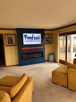 A living room with a fireplace, two armchairs, and a large sign above the fireplace.