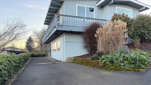 A modern two-story house with a balcony, a stone wall, and a variety of plants. - Stunning water and mountain views, steps from Old Town Silverdale. (Silverdale)