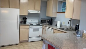 A kitchen with light wooden cabinets, a white refrigerator, a stove, a microwave, and a sink. - Stunning water and mountain views, steps from Old Town Silverdale. (Silverdale)