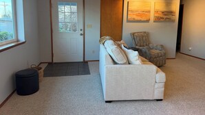 A living room with a beige sofa, a patterned armchair, a door with a window, and two paintings on the wall. - Stunning water and mountain views, steps from Old Town Silverdale. (Silverdale)