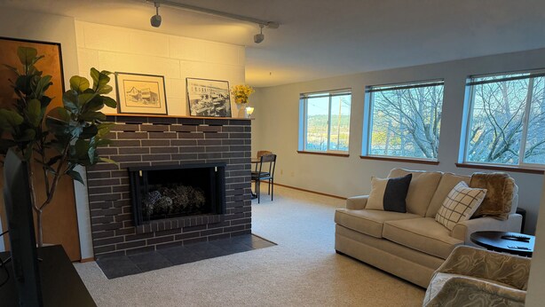 A living room with a fireplace, a sofa, and a coffee table. - Stunning water and mountain views, steps from Old Town Silverdale. (Silverdale)