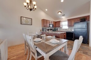 A modern kitchen with wooden cabinets, a black refrigerator, and a dining area with a wooden table and white chairs. - 6 Mi to Branson Strip: Resort Condo w/ Perks (Reeds Spring)