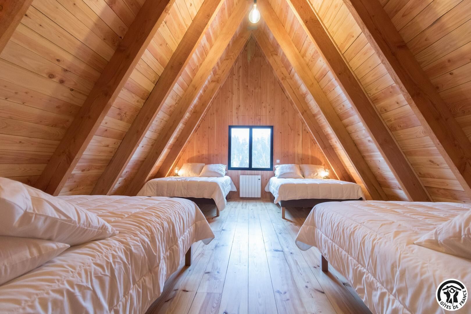 Een gezellig slaapkamer op zolder met houten balken, twee bedden, een raam en een radiator.