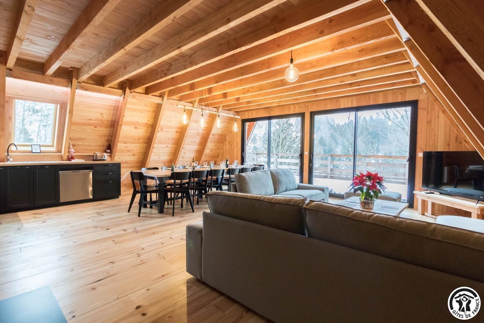 A spacious loft-style room with a dining area, a sofa, and a TV.