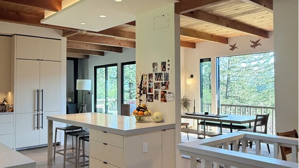 A modern kitchen with a central island, wooden ceiling beams, and large windows offering a view of the outdoors. - Epic views, modern luxury, private retreat in West Marin on hilltop 2 acre (Lagunitas-Forest Knolls)