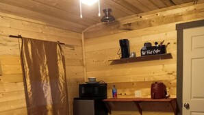 A small, cozy room with a bed, a desk, a microwave, a coffee maker, and a water bottle. - Buffalo Camp #7 (East Glacier Park)
