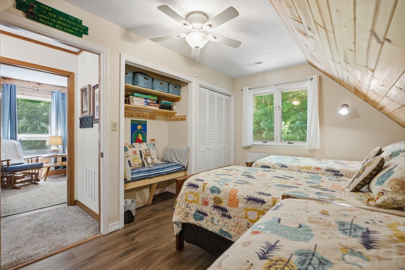 A bedroom with a bed, a chair, a desk, a bookshelf, and a window.