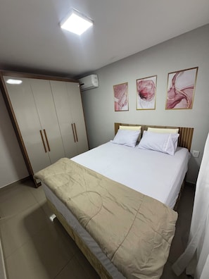 A bedroom with a bed, a wardrobe, and three wall-mounted paintings.
