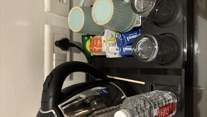 Eine Küche mit Wasserkocher, zwei Tassen, einer Kaffeemaschine und mehreren Wasserflaschen.