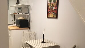 A compact kitchen with a microwave, a small table, and chairs. A painting is on the wall above the table. - Charming 1-bedroom apartment with AC in peaceful Nyack (Nyack)