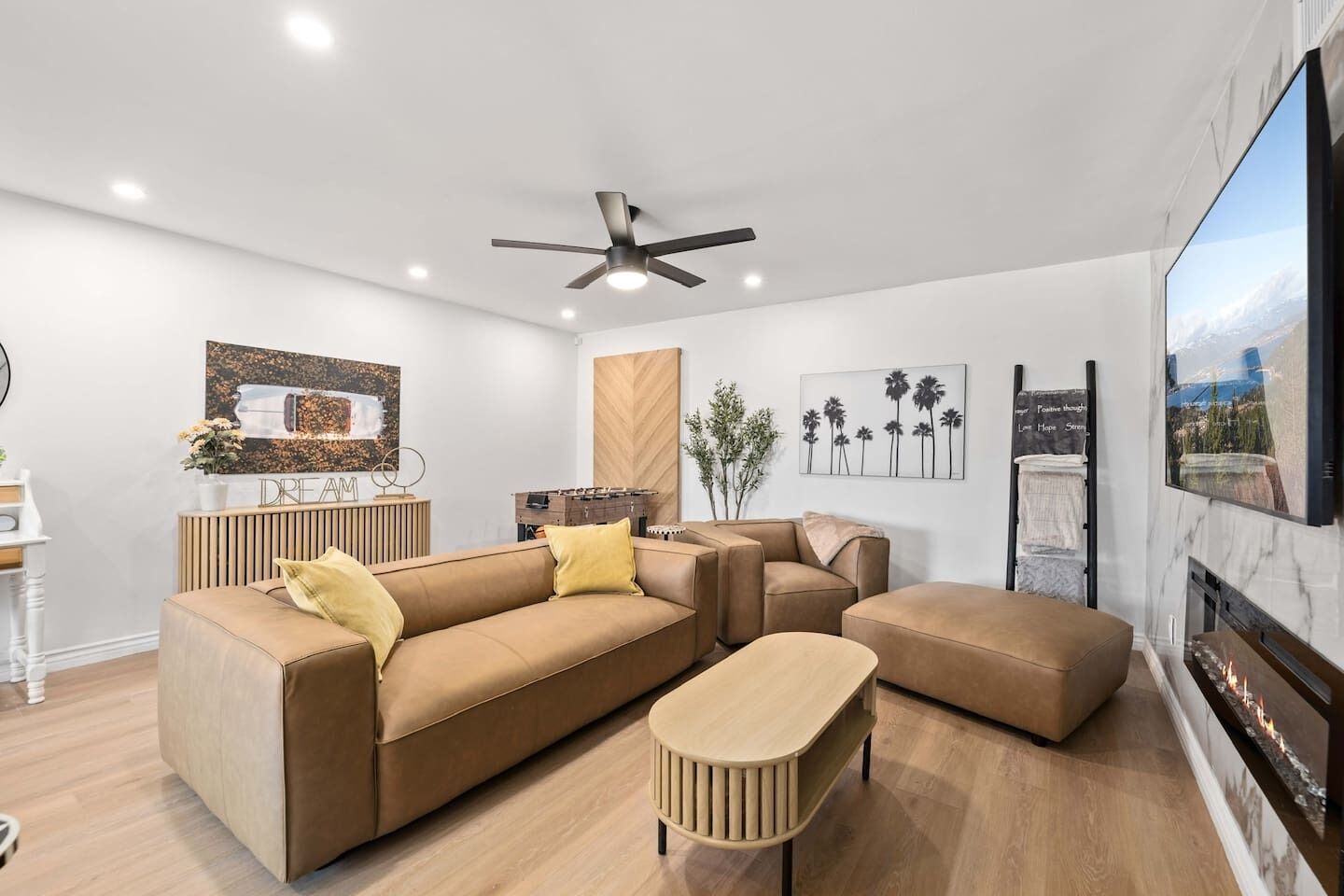 A modern living room with a brown sofa set, a wooden coffee table, and a ceiling fan.