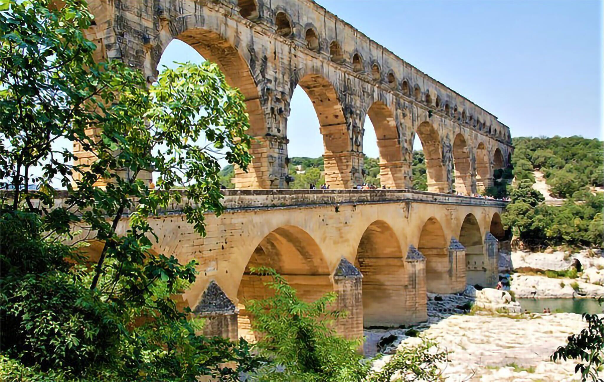 Un puente de piedra grande con varios arcos sobre un río, rodeado de vegetación.